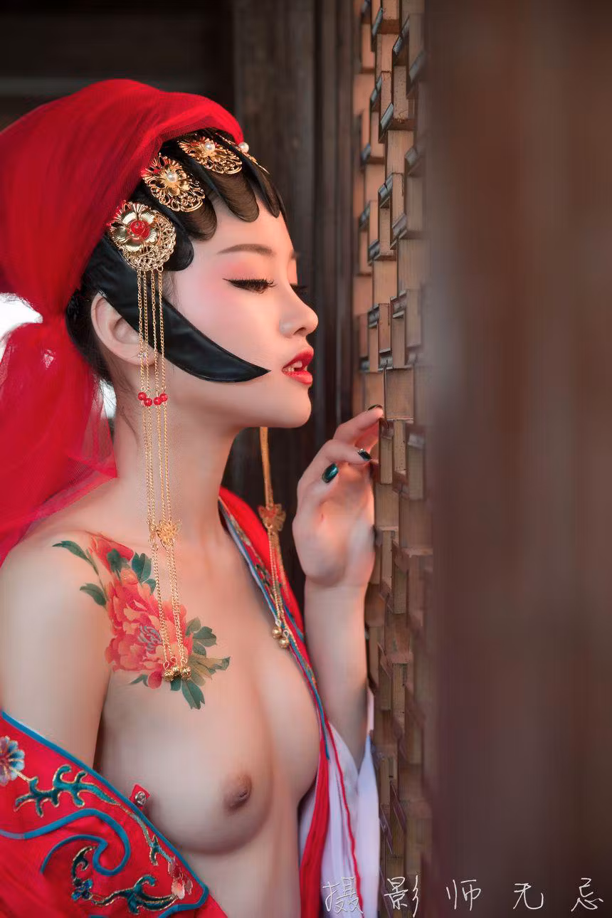 模特身穿红色古典戏服戴着头饰在中式木窗前侧身半露胸部摆拍